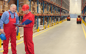 Workers in red overalls consulting in warehouse